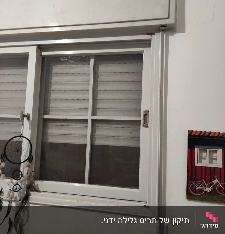 תריסים לבנים סגורים על חלון עם מסגרת לבנה